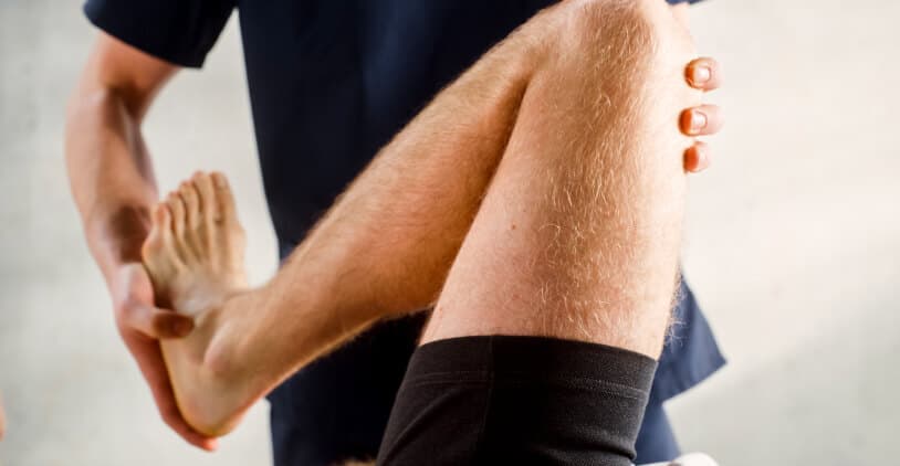 Therapeut voert een stretching oefening uit met een patiënt.